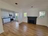 Kitchen featuring flat-panel white cabinetry, dark countertops, and stainless steel appliances, paired with wood-finish flooring and a central firepla