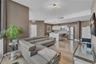 Open-concept living space featuring high-gloss cabinetry, stainless steel appliances, wood-finish flooring, and contemporary geometric light fixtures