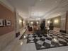 Grand entrance hall featuring patterned stone flooring, decorative stone-clad columns, recessed ceiling lighting, wall-mounted sconces, and crown mold