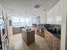 Kitchen featuring two-tone cabinetry, central island, stone-finish countertops, tile flooring, and integrated stainless steel wall oven