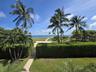 Manicured privacy hedges, mature palm trees, paved stone pathways, and open coastal water frontage