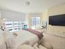 Expansive floor-to-ceiling windows, sliding glass door access to a private balcony, custom wall molding, neutral carpeting, and a ceiling-mounted ligh
