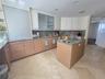 Kitchen featuring wood-finish cabinetry, stone countertops, central island, frosted glass cabinet inserts, and tile flooring