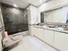 Bathroom featuring stone-tiled walls with decorative mosaic trim, dual-sink vanity with solid-surface countertop, frameless glass shower enclosure, an