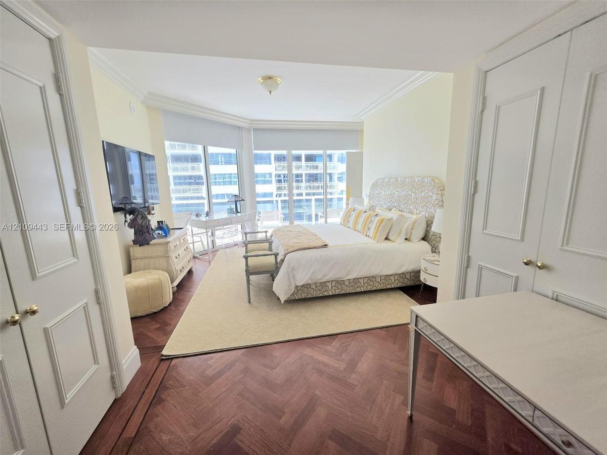 Herringbone wood-finish flooring, floor-to-ceiling windows, double-door closet cabinetry, and crown molding