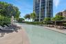 Swimming pool featuring stone-tile decking, a covered outdoor bar area, and mature landscaping