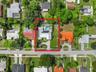 Aerial view of property featuring a single-story residence with rooftop solar panels, a rectangular swimming pool, and mature perimeter trees on a lar