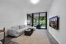 Living area featuring wood-finish flooring, floor-to-ceiling sliding glass doors, and a glass-railed balcony