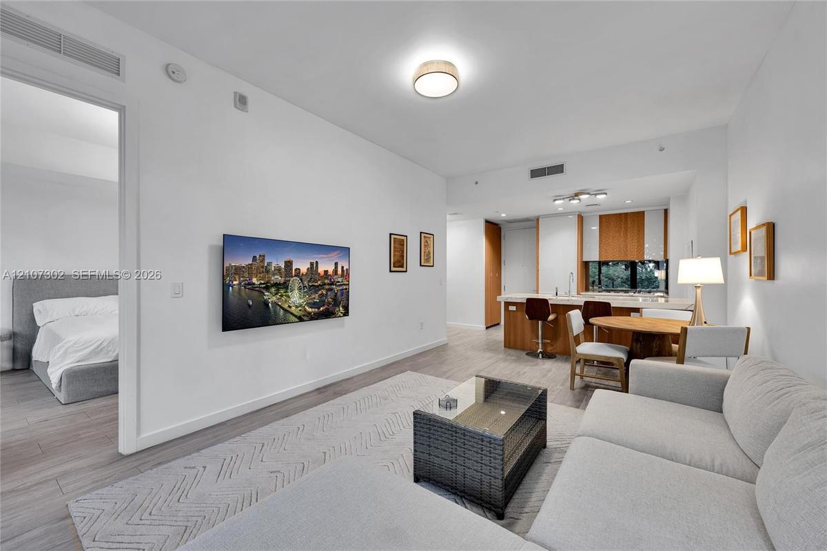 Open-concept living space featuring wood-finish flooring, recessed lighting, and a kitchen island with stone-finish countertops and wood-grain cabinet