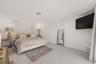 Neutral-toned interior featuring large-format tile flooring, recessed ceiling lighting, and a custom upholstered wall-mounted headboard