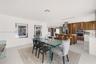 Open-concept interior featuring large-format tile flooring, recessed lighting, and a modern kitchen with wood-finish cabinetry, built-in stainless ste