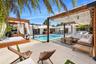 Outdoor living area featuring a custom concrete patio, rectangular swimming pool, integrated wood-beam pergolas, and built-in masonry structures