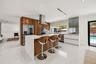 Kitchen featuring custom wood-finish cabinetry, a large central island with a quartz countertop, stainless steel appliances, a stacked-stone backsplas