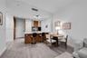 Kitchen featuring a stone-topped island with wood-finish cabinetry, floor-to-ceiling high-gloss white pantry storage, and wood-finish flooring