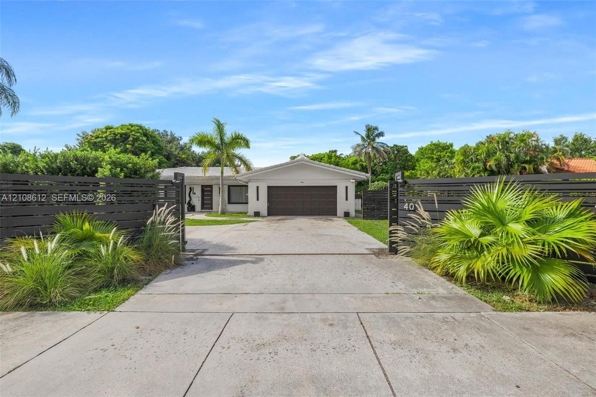 Single-story residence featuring a two-car garage, concrete driveway, horizontal slat fencing, and mature landscaping