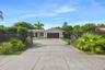 Single-story residence featuring a two-car garage, concrete driveway, horizontal slat fencing, and mature landscaping