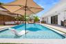 Swimming pool with a baja shelf, concrete pool deck, and built-in outdoor kitchen with a stainless steel grill