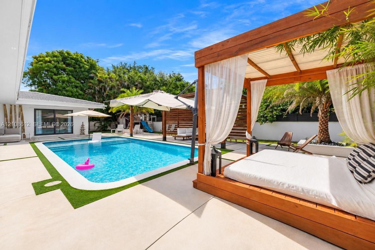 Backyard featuring a rectangular swimming pool, concrete patio surfacing, custom wood-framed pergola, and perimeter privacy fencing