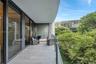 Covered balcony featuring large-format stone-finish tile flooring, floor-to-ceiling glass paneling, and a clear glass railing
