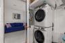 Stacked front-load laundry appliances with integrated shelving and white tile flooring