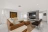 Open-concept room featuring high-gloss flooring, recessed lighting, and a floor-to-ceiling stone-tiled accent wall with a built-in linear fireplace an