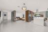 Open-concept interior featuring large-format tile flooring, a central wood-finish cabinetry partition with integrated stainless steel appliances, a ki