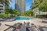 Swimming pool featuring stone pavers, metal pool ladder, and palm tree landscaping