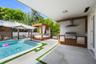 Covered outdoor kitchen featuring stainless steel grill, stainless steel range hood, and vertical slat cabinetry
