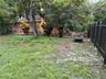 Backyard area featuring mature trees, peripheral landscaping, and a vertical metal privacy fence