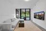 Living area featuring floor-to-ceiling glass sliding doors, wood-finish flooring, and an exterior balcony with glass railing