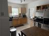 Kitchen featuring cabinetry with light-finish wood doors, stone-finish countertops, ceramic tile flooring, and integrated stainless steel appliances