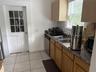 Kitchen featuring wood cabinetry, laminate countertops, a double-basin stainless steel sink, stainless steel dishwasher, and ceramic tile flooring