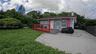 Single-story exterior featuring a red-painted wood deck, concrete driveway, and solid fence perimeter