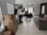 Open-concept interior featuring neutral ceramic tile flooring, oversized multi-pane windows, and a ceiling-mounted fan