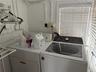 Dedicated laundry area featuring a top-load washer, a built-in dryer, white wall-mounted garment rack, and horizontal slat window blinds