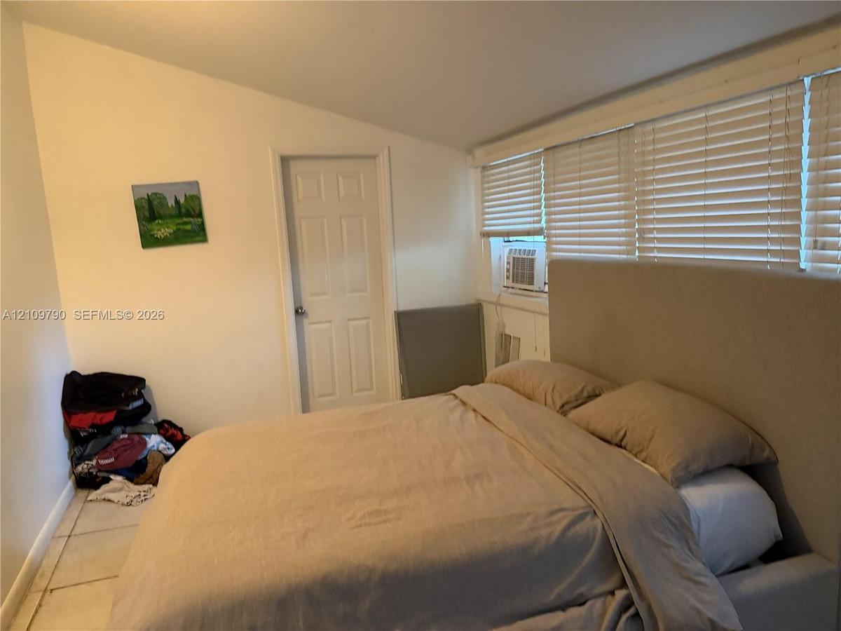 Room with sloped ceiling, tile flooring, and large windows featuring horizontal blinds