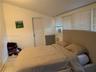Room with sloped ceiling, tile flooring, and large windows featuring horizontal blinds
