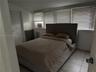 Room featuring neutral tile flooring, a multi-panel door, and a wall of windows fitted with horizontal blinds