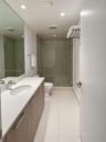 Vanity featuring a light wood-finish cabinet, white solid-surface countertop, and an integrated basin with a polished chrome faucet