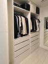 Custom floor-to-ceiling cabinetry with integrated hanging rods, extensive drawer storage, overhead shelving, and an inset full-length wall mirror