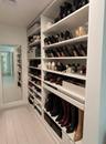 Custom floor-to-ceiling white shelving with multiple storage tiers and a full-length wall mirror