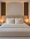 Textured stone accent wall featuring vertical wood-slat detailing, integrated perimeter lighting, and dual wall-mounted floating bedside fixtures