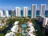 Aerial perspective of a multi-unit property complex featuring tennis courts, a swimming pool, and direct canal access