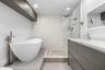 Freestanding soaking tub with floor-mounted faucet, walk-in glass-enclosed shower featuring mosaic stone flooring, dark wood-finish cabinetry, illumin