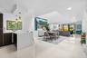 Open-concept living space featuring white polished tile flooring, recessed ceiling lighting, a waterfall-edge kitchen island, dual pendant lights, and