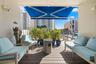 Covered balcony featuring wood-finish composite decking, a retractable fabric awning, and integrated wall-mounted lighting