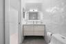 Floating vanity with a smooth-finish countertop, integrated under-mount sink, geometric textured tile walls, and a backlit mirror