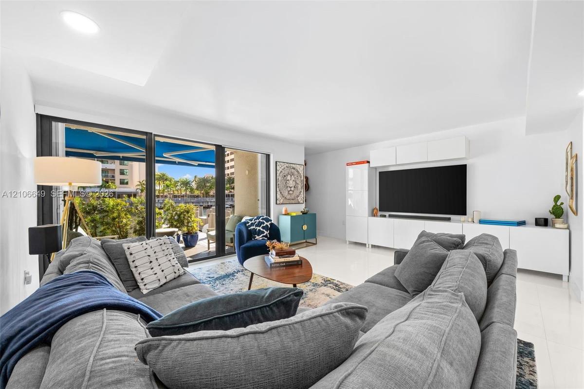 Hallway featuring polished tile flooring, recessed lighting, and a bathroom equipped with a floating vanity, light-toned wood-finish cabinetry, and a 