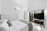 Vaulted ceilings, large sliding glass doors, white tiled flooring, and louvered closet doors