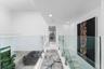 Hallway featuring glass panel railings, metal hardware, stone-finish flooring, and recessed ceiling lighting